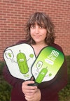 a woman holding paddles with pickles on them