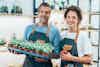 a man and woman holding a tray of plants