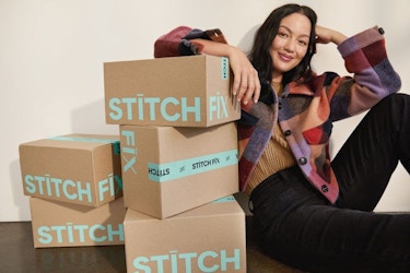  A woman poses next to several stacked Stitch Fix-labeled boxes. 