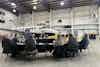a group of people sitting around a table in a hangar with a plane in the background